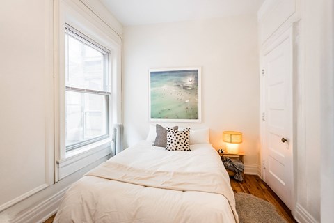 A bedroom with a white bed and a painting on the wall.