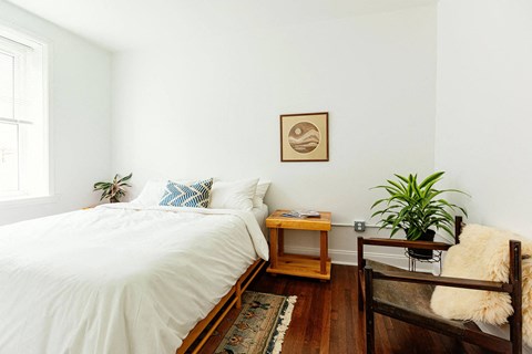 A bedroom with a white bed and a wooden bench.