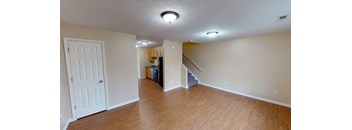 an empty living room with wood floors and a staircase
