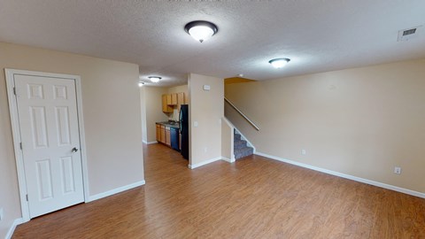 an empty living room with wood floors and a staircase