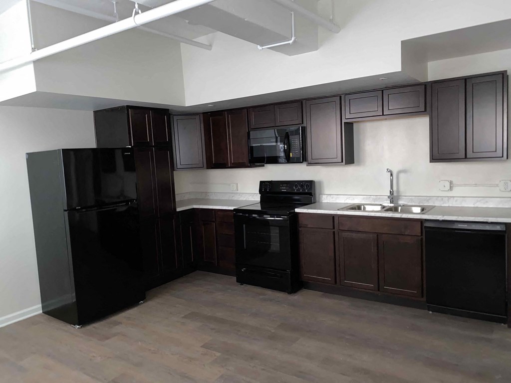 an empty kitchen with black appliances and dark wood cabinets
