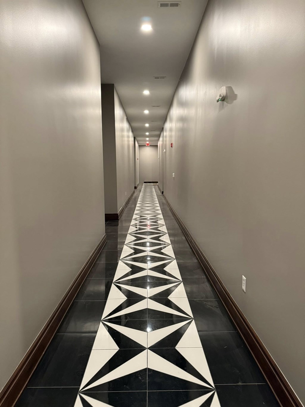 A long hallway with a black and white floor design.