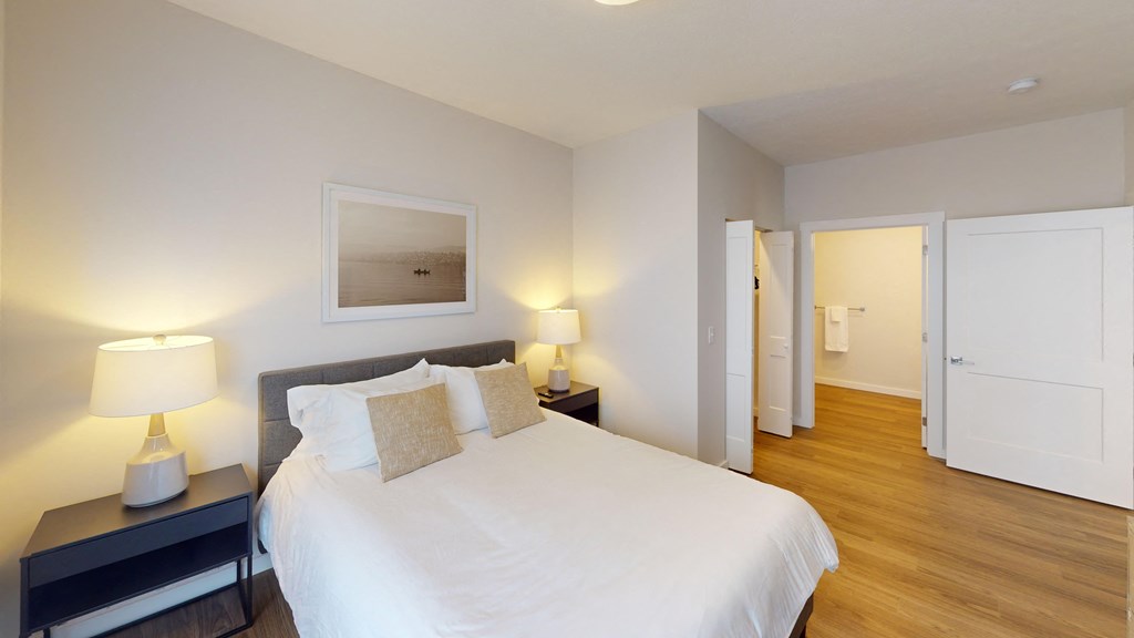 Bedroom with a large white bed and a wooden floor at The Landing Apartments, Indiana