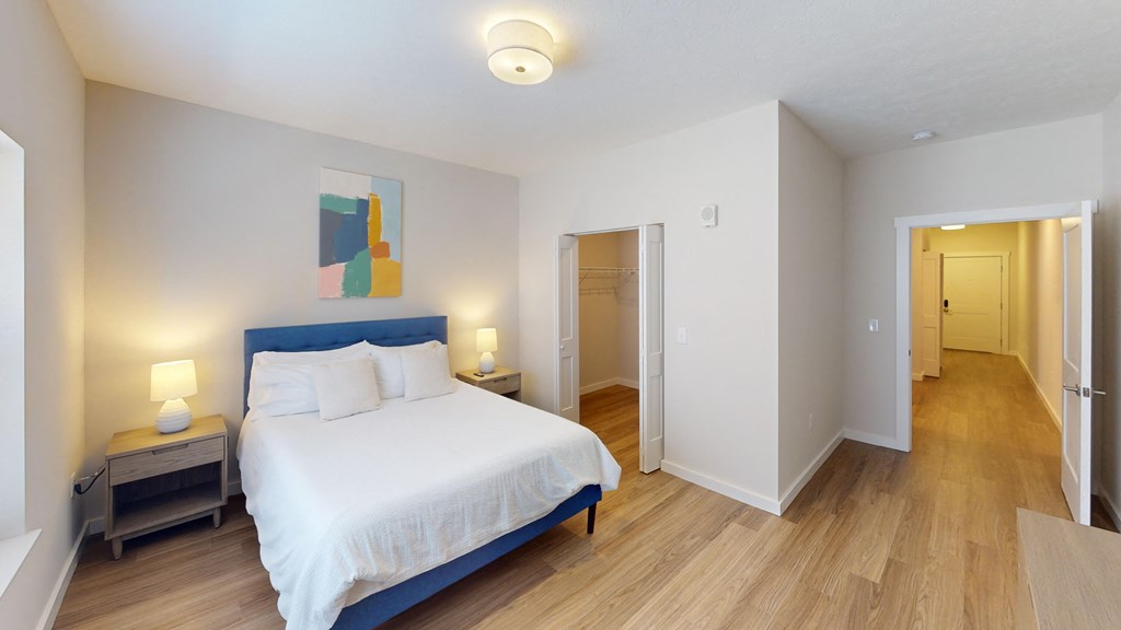 Bedroom with a large bed and a door to a hallway at The Landing Apartments, Indiana