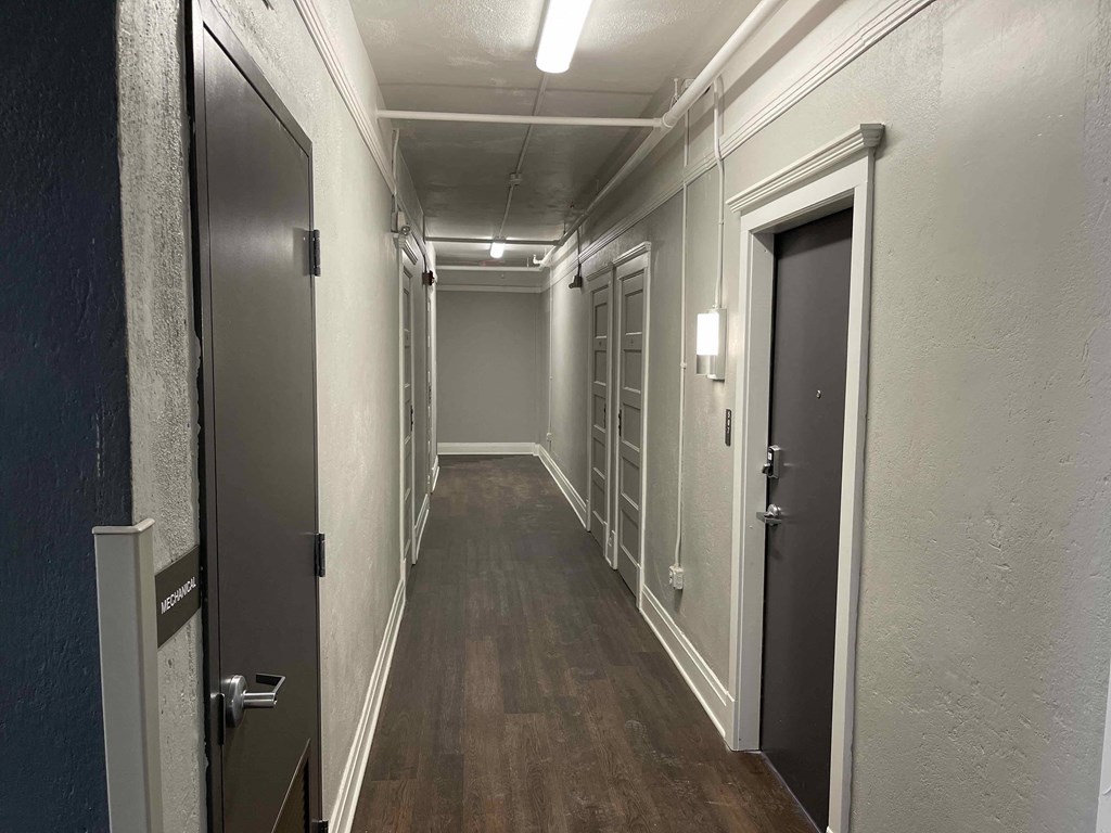 a hallway with doors and white walls and wood floors