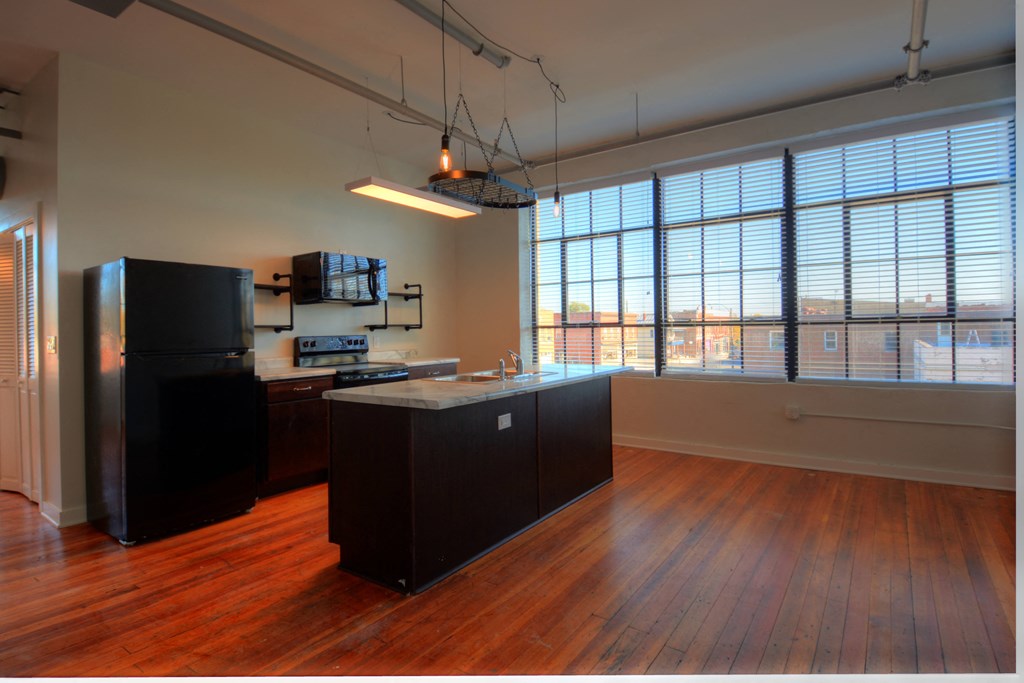 an empty kitchen with a large window and wood floors