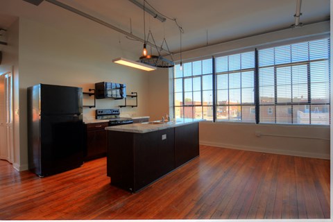 an empty kitchen with a large window and wood floors