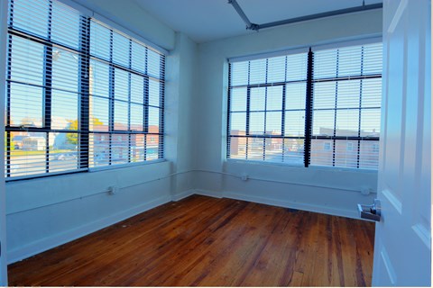 an empty room with wooden floors and large windows