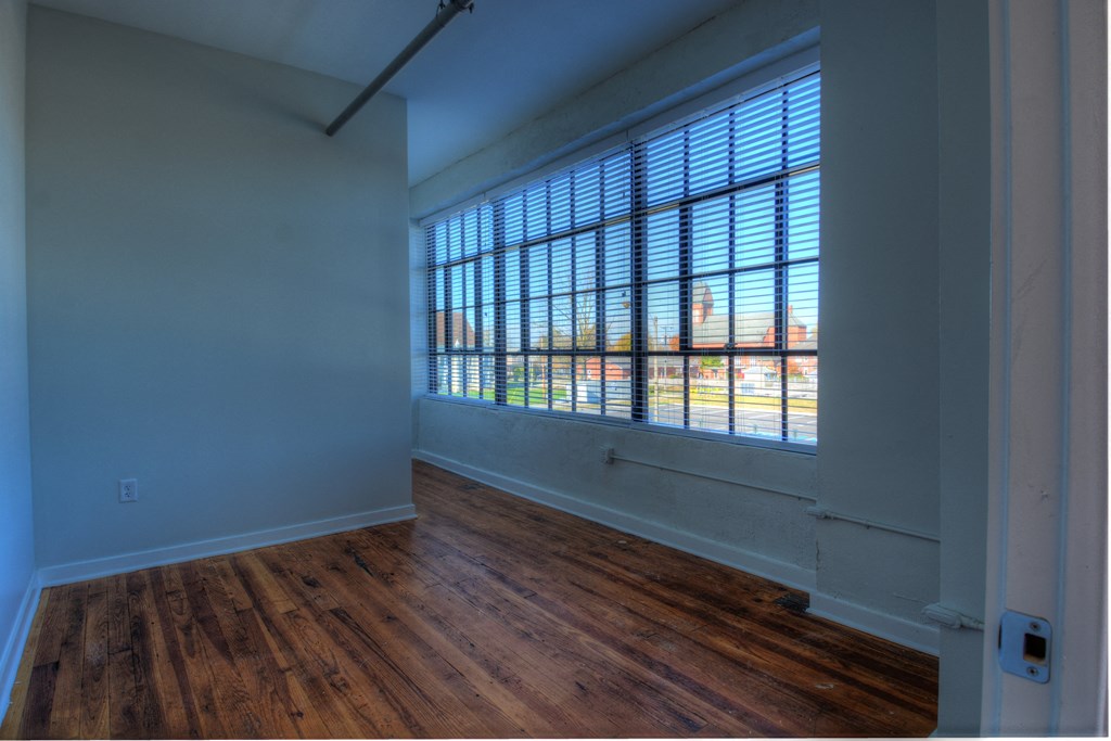 an empty living room with wood floors and a large window