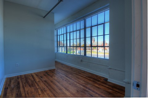 an empty living room with wood floors and a large window
