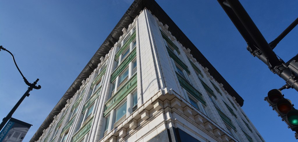 A tall building with a green awning is seen from below.