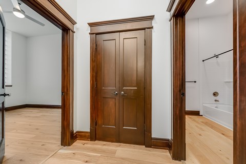 A wooden wardrobe stands in a room with a white wall and wooden floor.