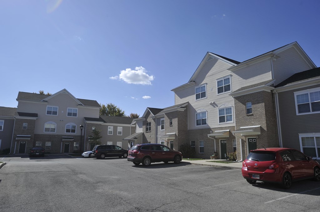 a row of apartment buildings with cars parked in a parking lot