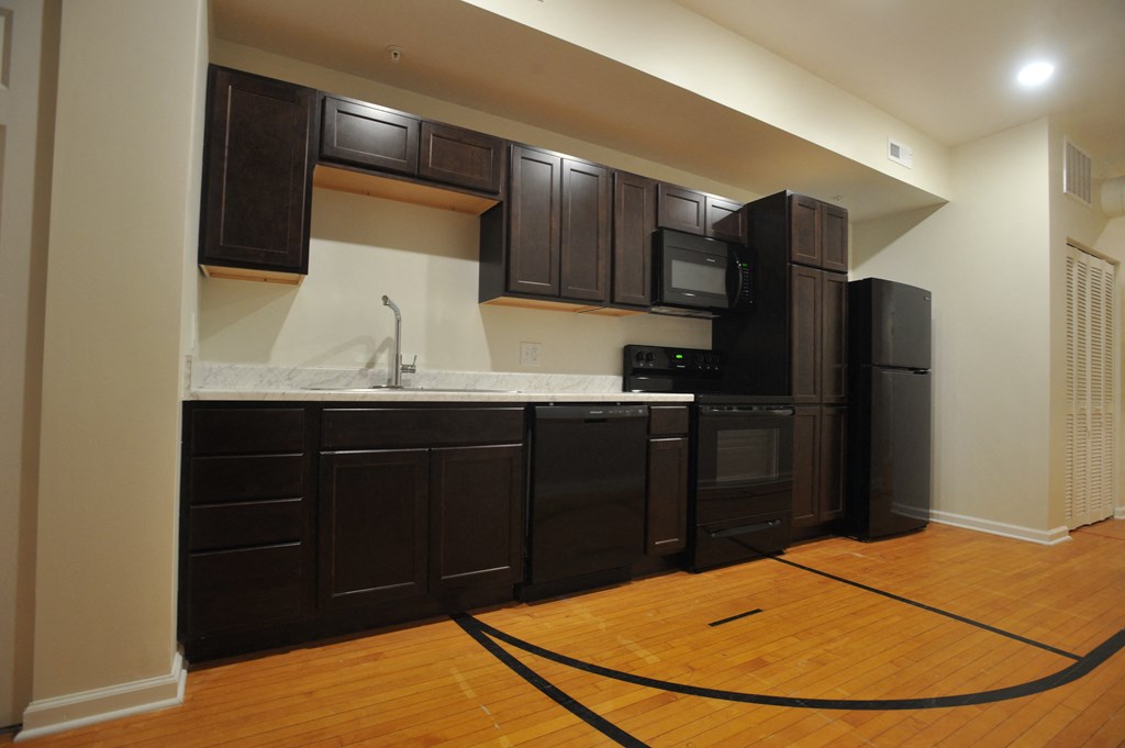 an empty kitchen with black appliances and a rope on the floor