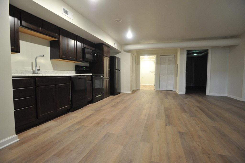 a kitchen and living room with wooden floors and black cabinets