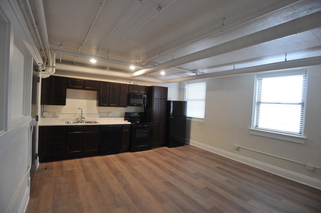 an empty kitchen with wooden floors and black cabinets