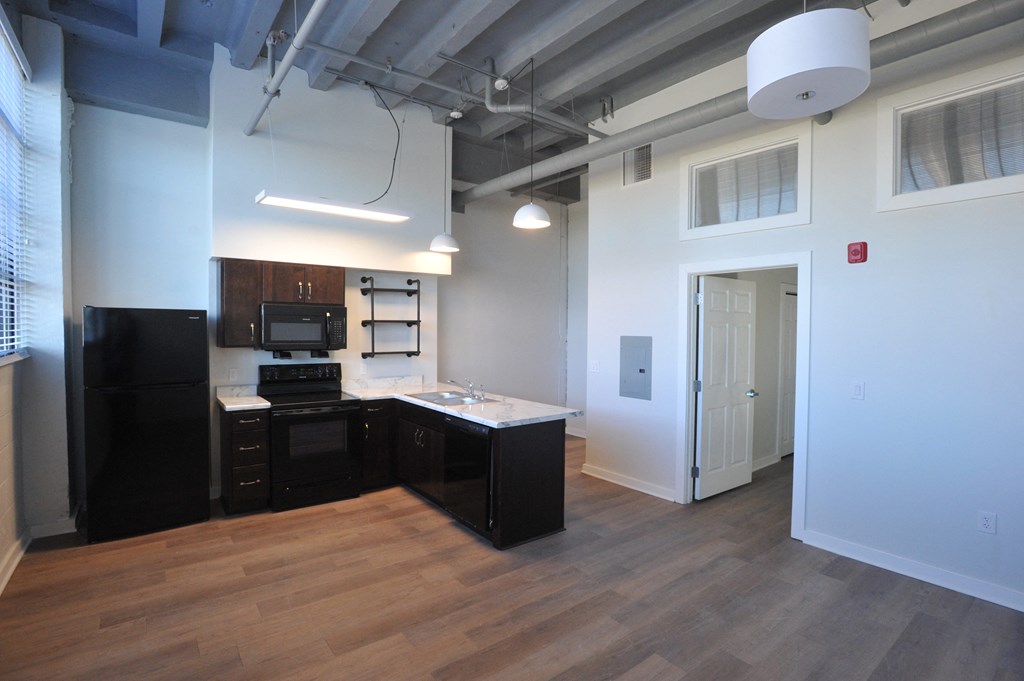 an open kitchen and living room with a wood floor and white walls