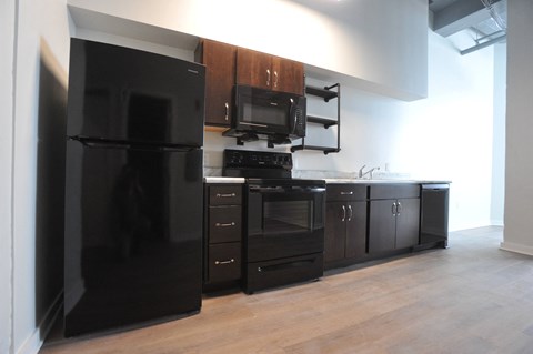 an empty kitchen with black appliances and wooden cabinets