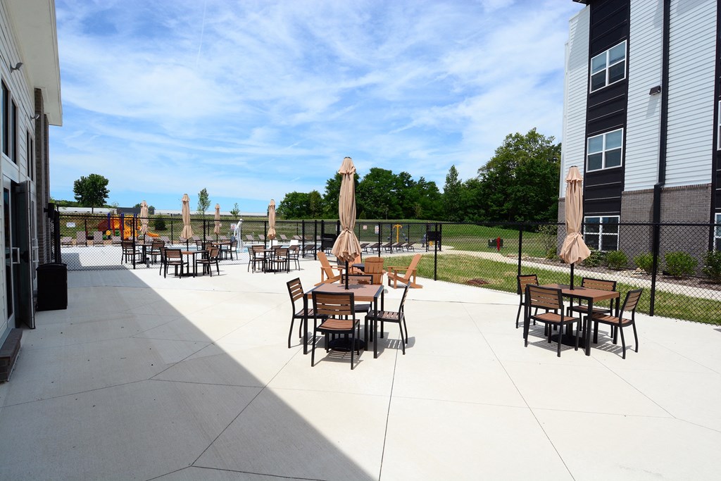 an outdoor patio area with tables and chairs and a fence
