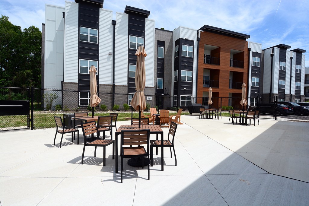 a patio with tables and chairs in front of an apartment building