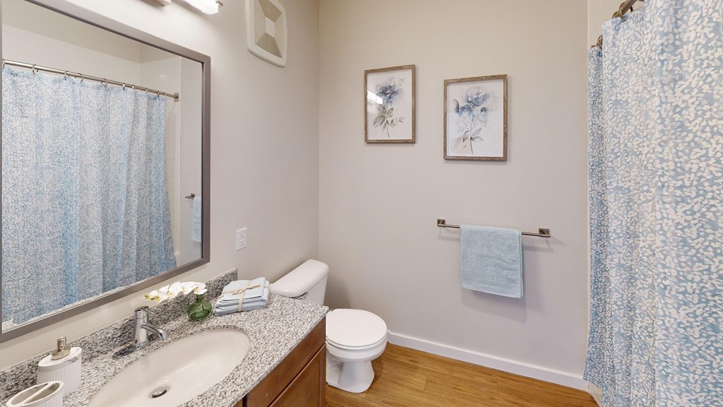 a bathroom with a mirror and a toilet and a sink  at The Landing Apartments, Indianapolis