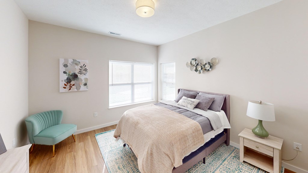 a bedroom with a bed and a chair and a window  at The Landing Apartments, Indiana