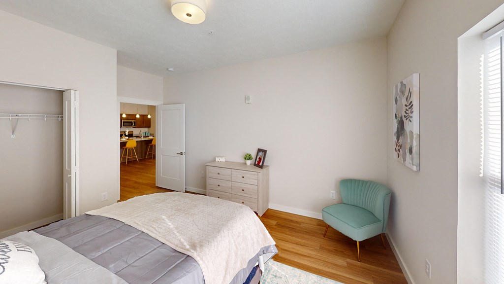 a bedroom with a bed and a chair and a closet  at The Landing Apartments, Indianapolis