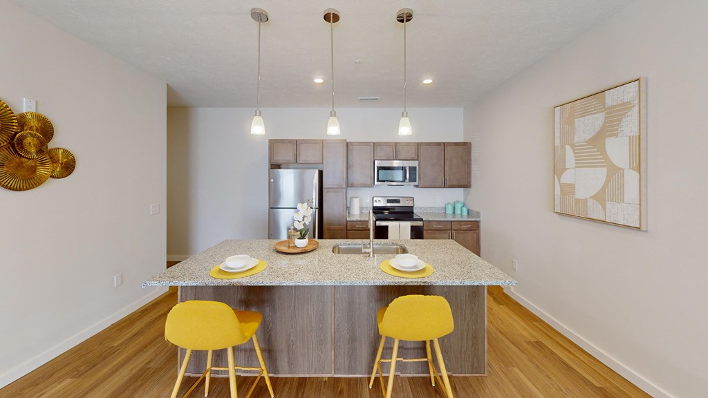 a kitchen with a marble counter top and yellow bar stools  at The Landing Apartments, Indiana