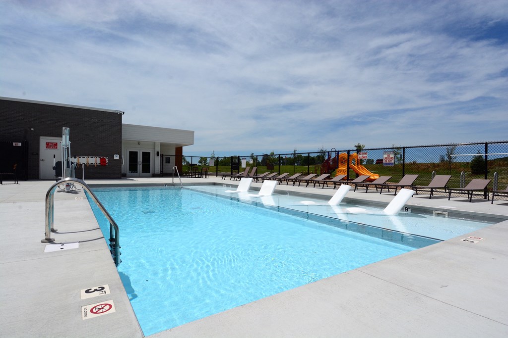 a swimming pool with chairs and a fence around it