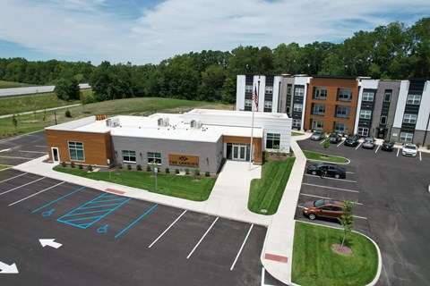 an aerial view of an apartment complex with parking lot and grass