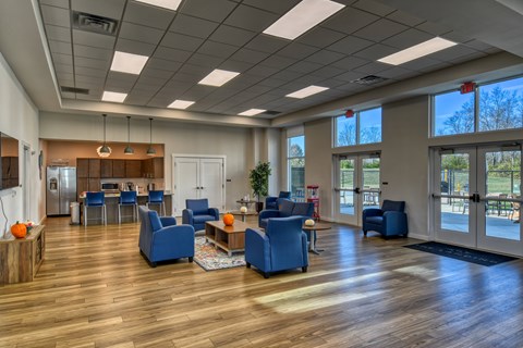 A spacious waiting room with blue chairs and a wooden floor at The Landing Apartments, Indianapolis