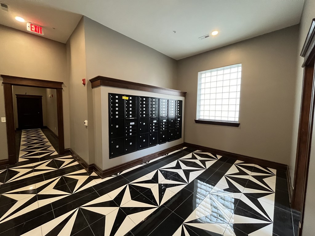 A hallway with a black and white tiled floor and a digital clock on the wall.