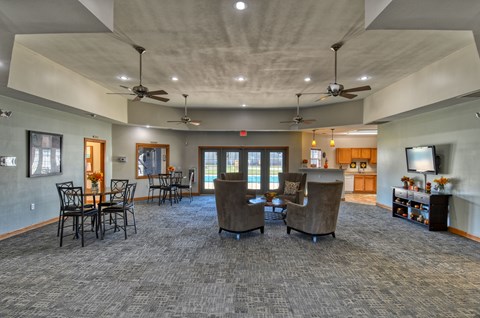 A spacious room with grey carpeting and a ceiling fan.