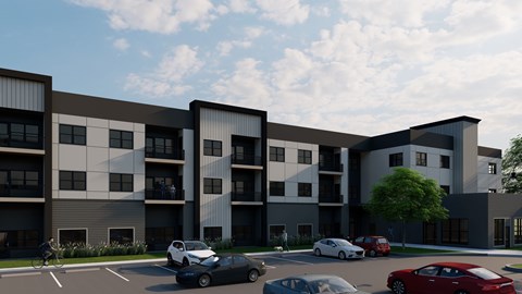 A modern apartment complex with cars parked in front.