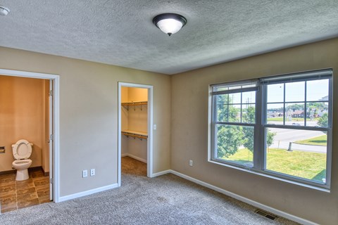A room with a toilet and a window overlooking a street.