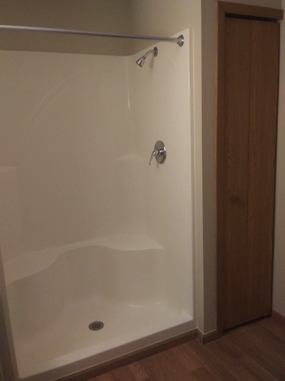 a white shower in a bathroom with a wooden floor
