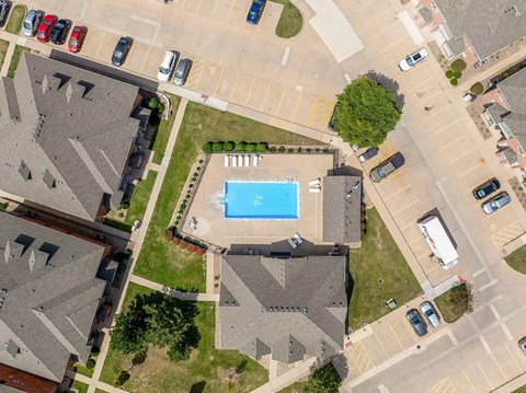A swimming pool is surrounded by houses and cars.