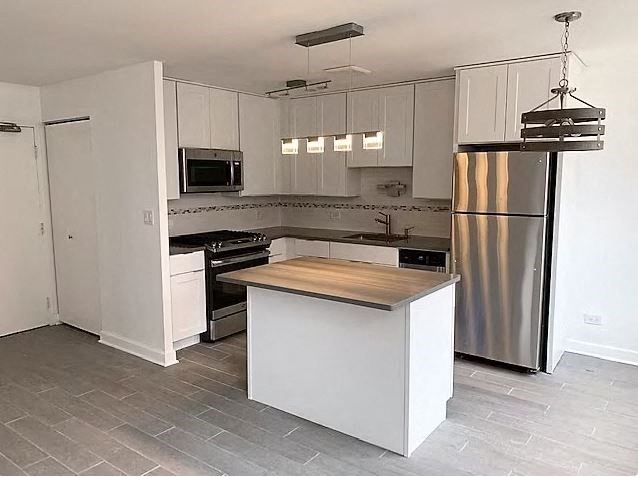 A kitchen with a white island and stainless steel appliances.