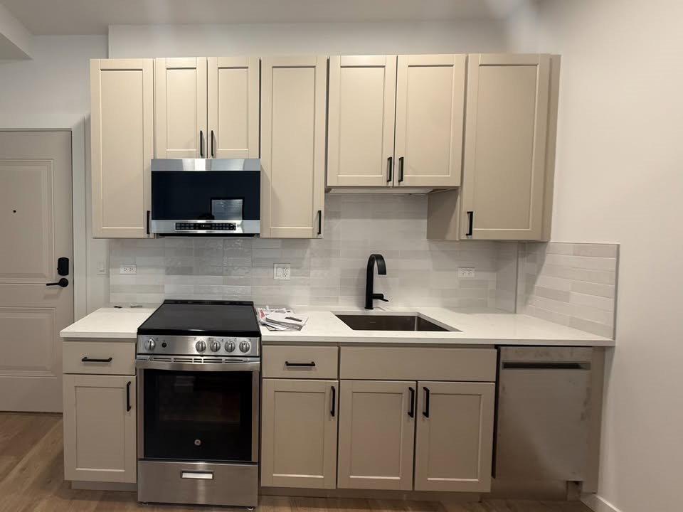 A kitchen with a stove top oven, microwave, and cabinets.at The Nest at Lincoln Park West, Illinois