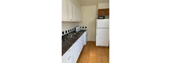 A kitchen with white cabinets and a white fridge.
