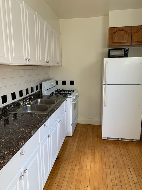 A kitchen with white cabinets and a white fridge.