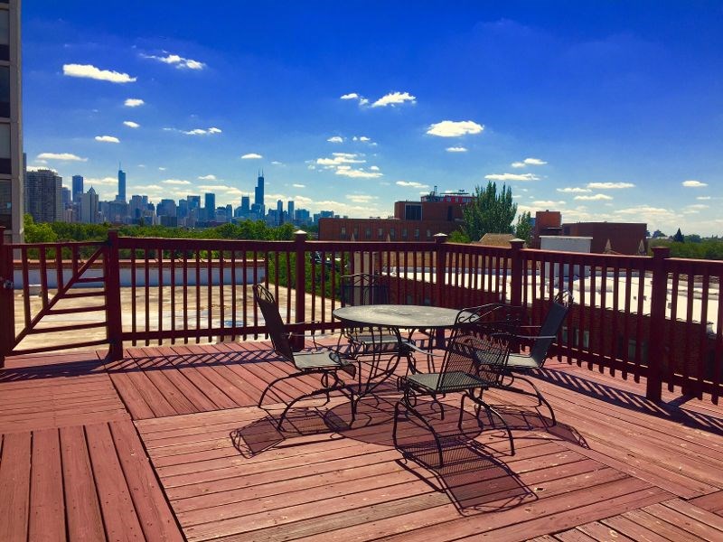 A wooden deck with a table and chairs overlooking a city skyline.
