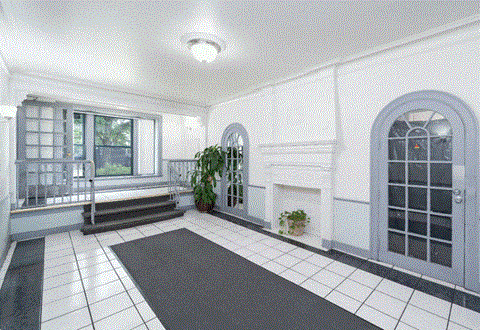 A white and black tiled room with a fireplace and a potted plant.
