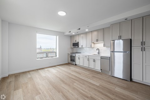A kitchen with white cabinets and a wooden floor.