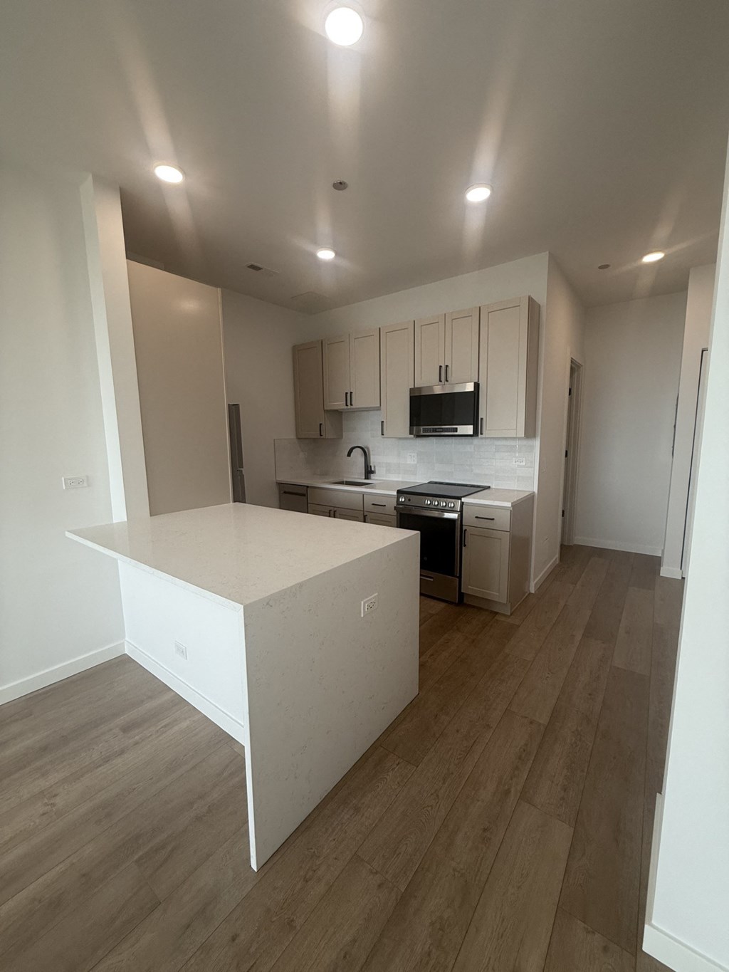 A kitchen with a white countertop and wooden floors.at The Nest at Lincoln Park West, Chicago