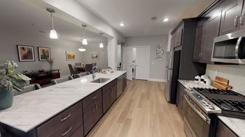 A modern kitchen with dark wood cabinets and a marble countertop.
