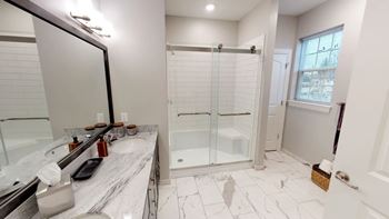 A bathroom with a marble countertop and a walk-in shower.
