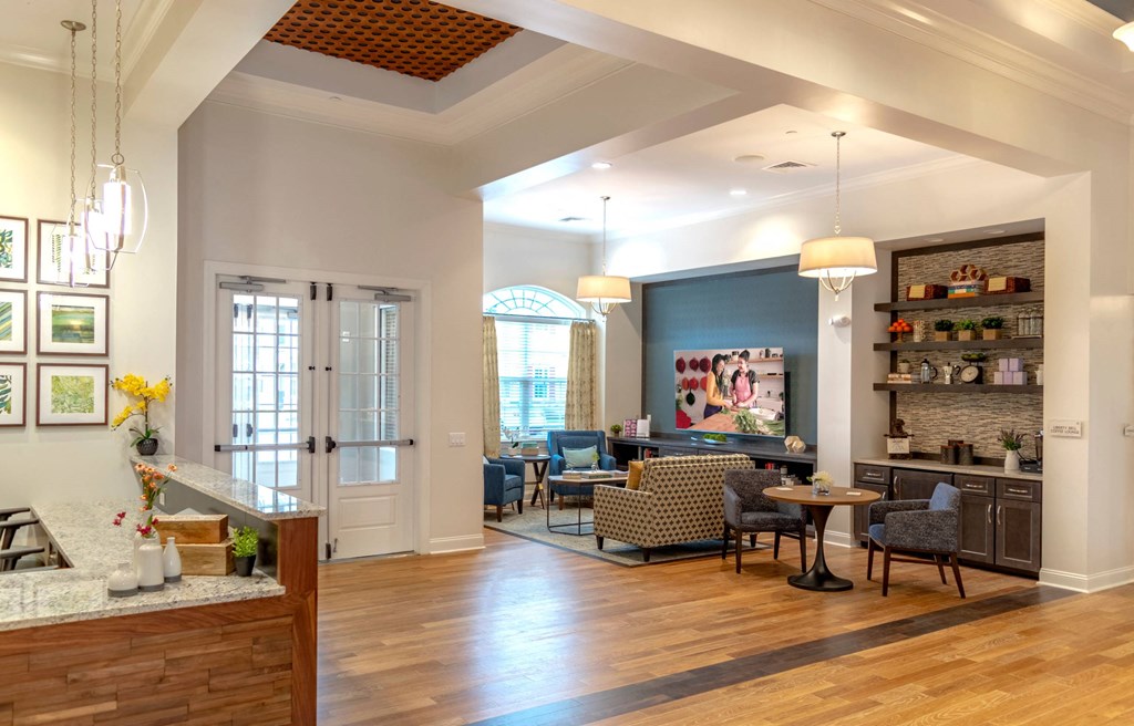 A well-lit, spacious living room with a dining area and kitchen in the background.