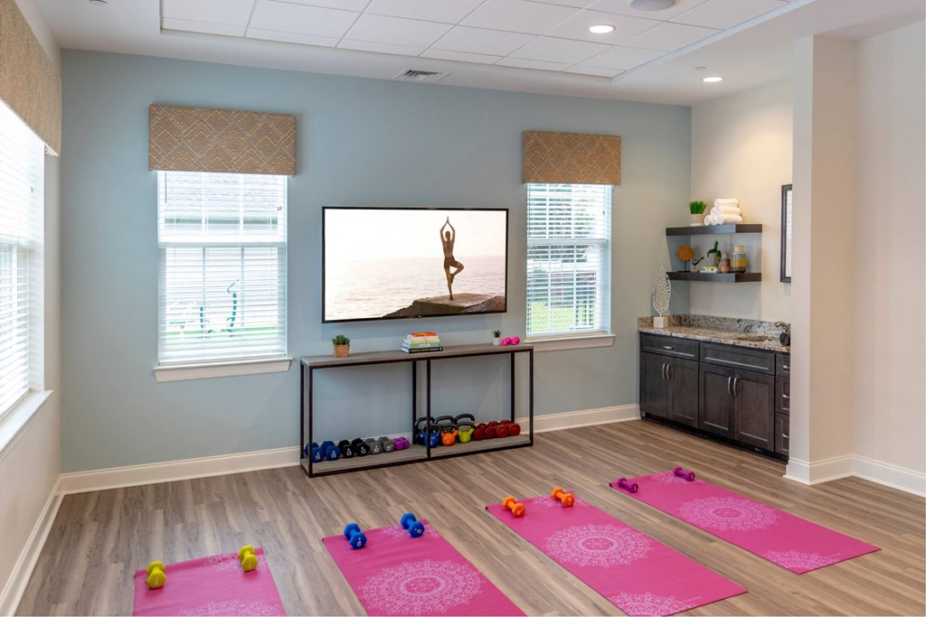 A yoga mat with a pink circle design is on the floor.