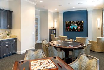 A room with a table, chairs, and a painting on the wall.